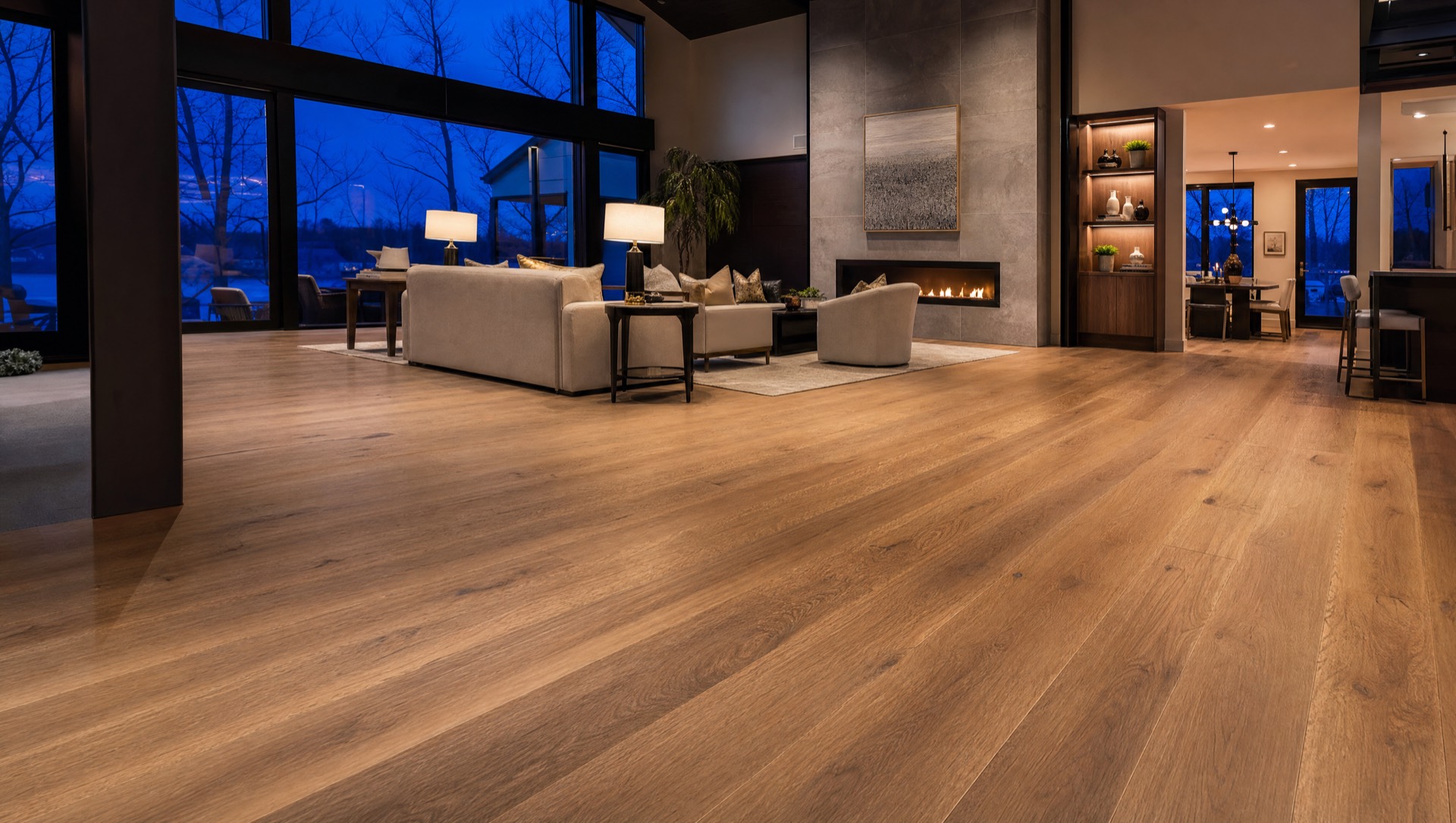 Wide-plank luxury vinyl flooring and a floor-to-ceiling tiled fireplace in a Minnesota home at dusk